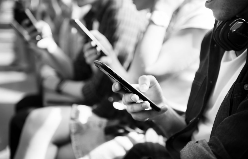 Group of young adult friends using smartphones in the subway